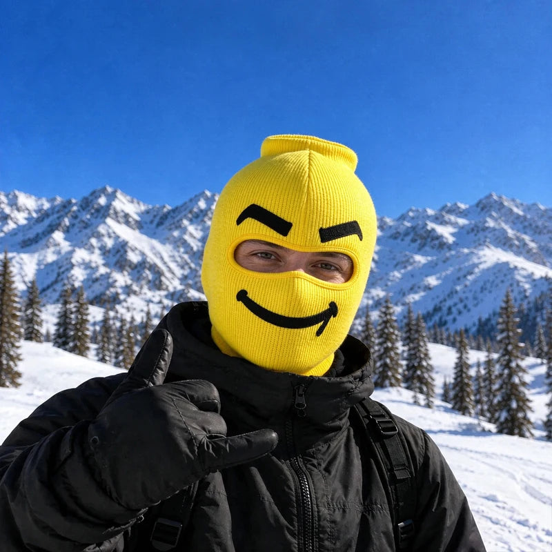 Smuggles yellow big head ski mask with a sly smirk and thick black eyebrows, worn on a snowy mountain