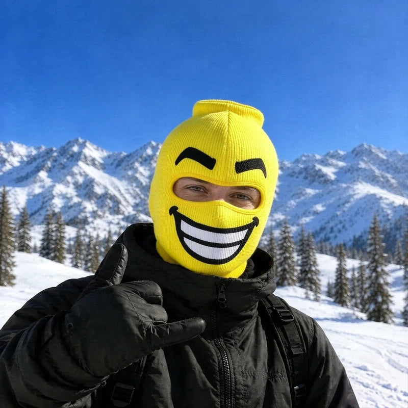 Beamer yellow big head ski mask with a huge toothy grin, worn on a snowy mountain