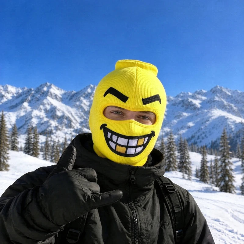 Chompers yellow big head ski mask with a gritted-teeth grin and one gold tooth, worn on a snowy mountain